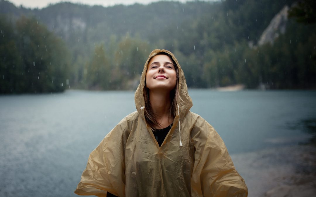 woman in raincoat near lake in rainy day.